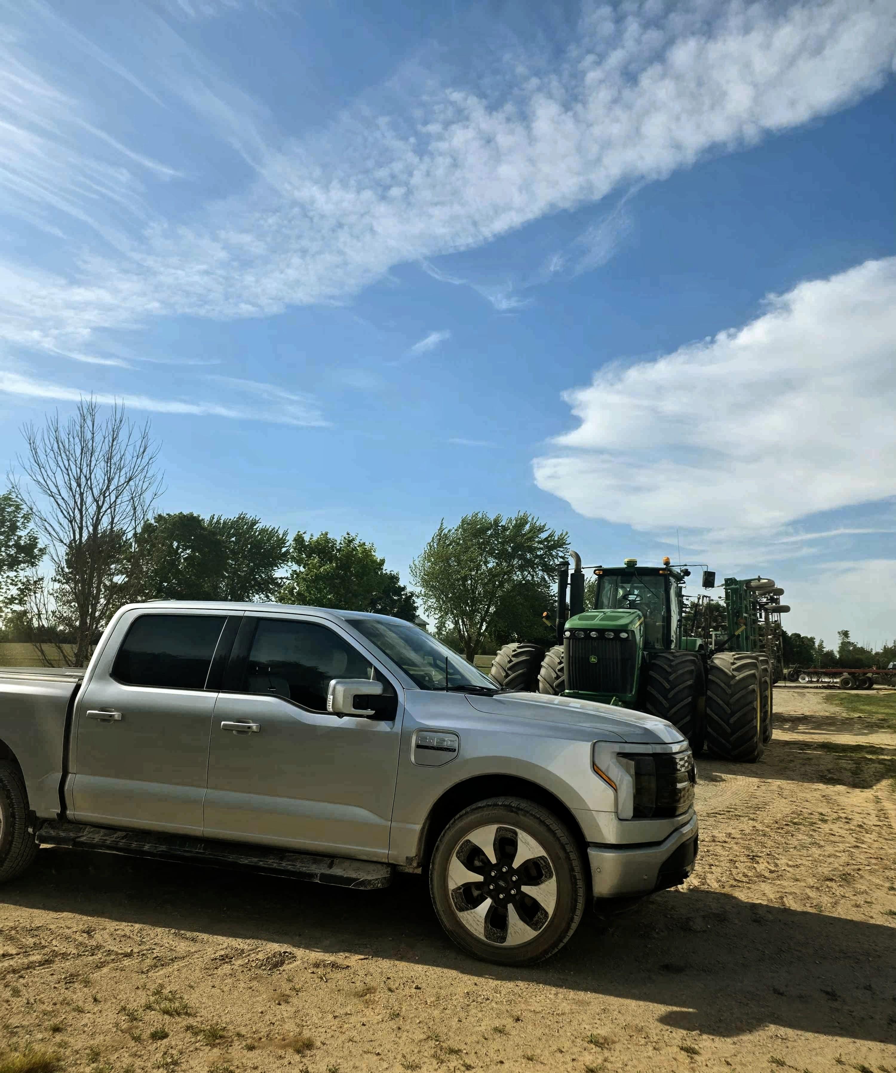 Ford F-150 Lightning on duty next to a John Deere tractor