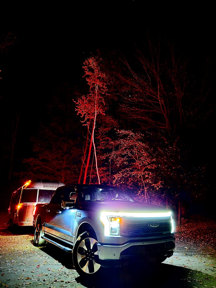F-150 Lightning illuminating an Airstream at night in the woods
